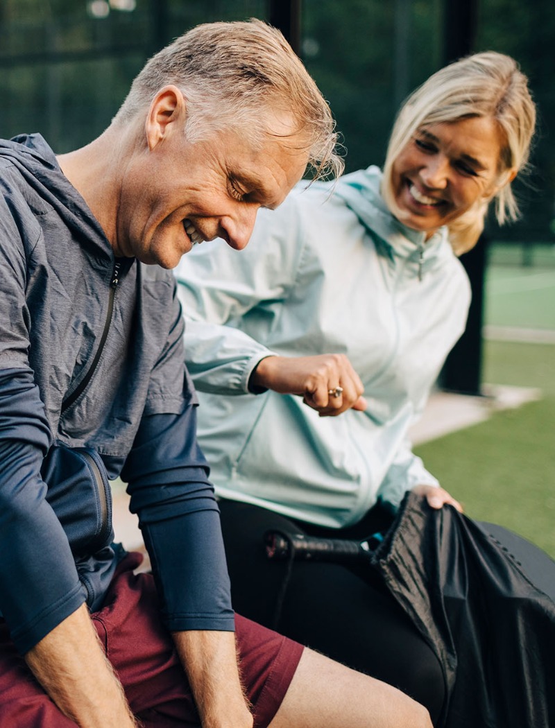 Voksen mann og dame som sitter på en benk i treningsklær
